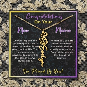 May include: A gold necklace with a flower charm and the name "Evelyn" spelled out in cursive. The necklace is displayed on a black card with the text "Congratulations on your new name" and "So Proud of You!"