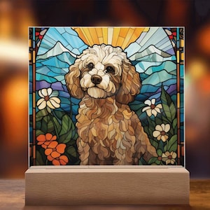 Op de afbeelding: Een afbeelding in de stijl van een glas-in-loodraam van een lichtbruine poedel die in een bloemenveld zit met een bergketen op de achtergrond.