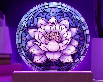 Puede incluir: Una luz nocturna de estilo vitral con un diseño de flor de loto púrpura y azul. La luz está sobre una base de madera.