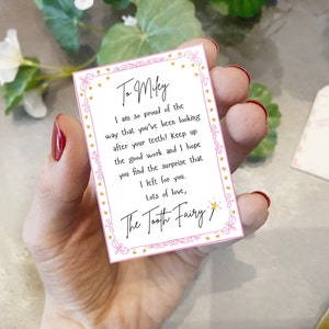 May include: A pink and white card with gold stars and a message for Milky from the Tooth Fairy. The message reads: "I am so proud of the way that you've been looking after your teeth! Keep up the good work and I hope you find the surprise that I left for you. Lots of love, The Tooth Fairy."