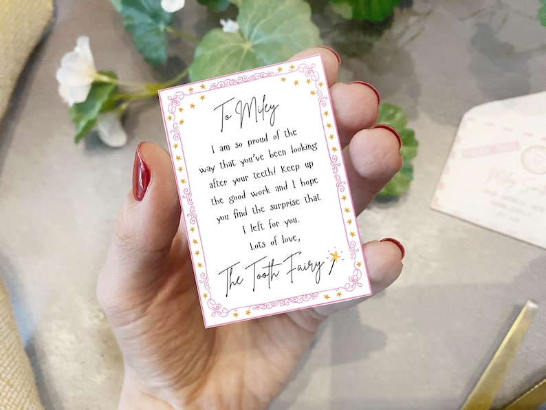 May include: A pink and white card with gold stars and a message for Milky from the Tooth Fairy. The message reads: "I am so proud of the way that you've been looking after your teeth! Keep up the good work and I hope you find the surprise that I left for you. Lots of love, The Tooth Fairy."