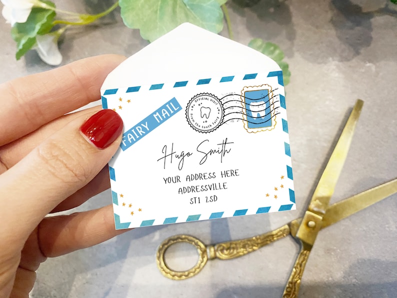 May include: A white envelope with a blue and gold design. The envelope has a stamp with a tooth on it and the words "Fairy Mail" written on it. The envelope is addressed to "Hugo Smith" with an address below.