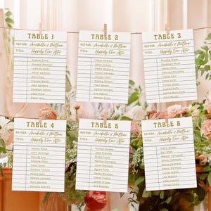 May include: Six table assignment cards with guest names, suspended by clothespins. Each card is labeled with a table number and the text "Happily Ever After". The cards are decorated with floral arrangements.