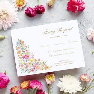 May include: A white RSVP card with a floral design in the corner. The text reads "Kindly Respond by October 1st 2024". There are two options to choose from: "Accepts with Pleasure" and "Declines with Regret".