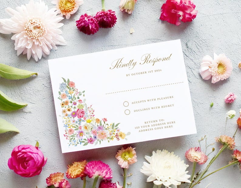 May include: A white RSVP card with a floral design in the corner. The text reads "Kindly Respond by October 1st 2024". There are two options to choose from: "Accepts with Pleasure" and "Declines with Regret".