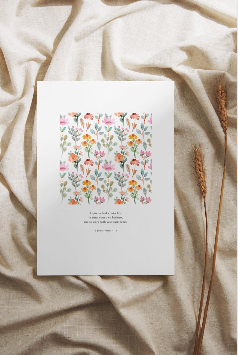 May include: A white printable art print with a watercolor floral pattern and a quote from 1 Thessalonians 4:11 that reads "Aspire to lead a quiet life, to mind your own business, and to work with your own hands."