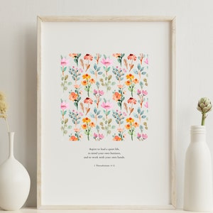May include: A framed print with a watercolor floral pattern and a quote from 1 Thessalonians 4:11. The quote reads: "Aspire to lead a quiet life, to mind your own business, and to work with your own hands."