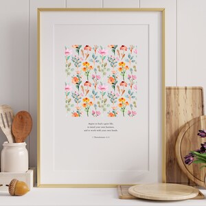 May include: A framed print with a watercolor floral pattern and a quote from 1 Thessalonians 4:11: "Agree to lead a quiet life, to mind your own business, and to work with your own hands."