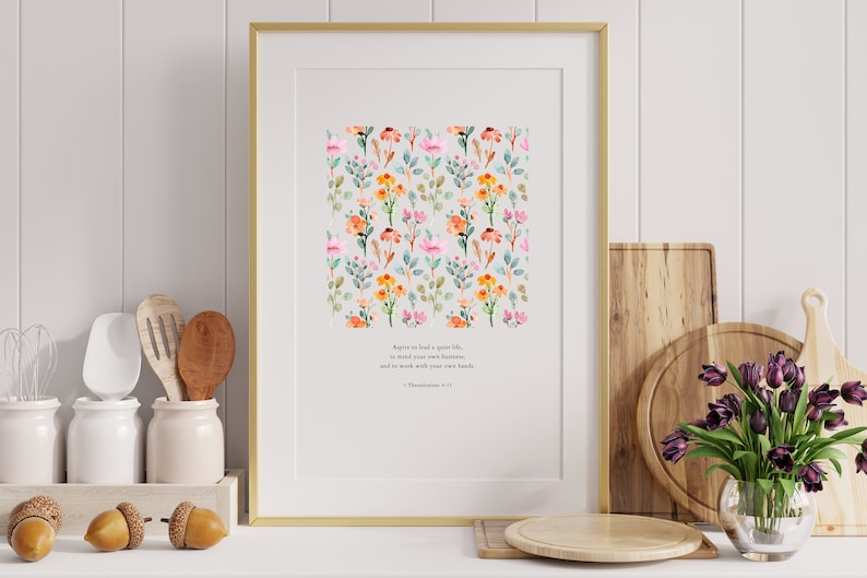 May include: A framed print with a watercolor floral pattern and a quote from 1 Thessalonians 4:11: "Agree to lead a quiet life, to mind your own business, and to work with your own hands."