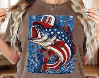 May include: A brown short-sleeve t-shirt featuring a graphic of a largemouth bass wearing a baseball cap. The fish is patterned with red and white stripes and blue stars, set against a background of vertical blue stripes and splashing water.