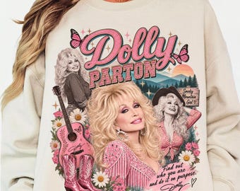 May include: A beige crewneck sweatshirt featuring a graphic print of Dolly Parton with pink text that reads Dolly Parton, a pink acoustic guitar, pink cowboy boots, butterflies, flowers, and the text Smoky Mountain Girl and Find out who you are and do it on purpose.