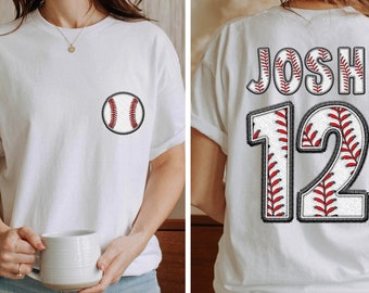 May include: White t-shirt with a baseball graphic on the front and the name "Josh" and the number "12" on the back, both with a baseball graphic design.