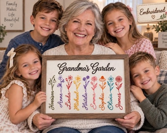 May include: A rectangular wooden framed sign with a white background featuring the text Grandma's Garden in black script. Below the text are nine colorful embroidered flower stems, each paired with a name in a matching color.