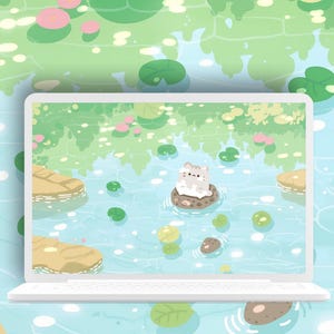 May include: A white laptop displays a whimsical illustration of a pond scene. The artwork features a cartoon cat on a lily pad, surrounded by lily pads and water. The background shows a green and blue pond with reflections.
