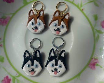 May include: Four pairs of dangle earrings featuring a husky dog face design. Two pairs have brown and white husky faces, and two pairs have black and white husky faces.
