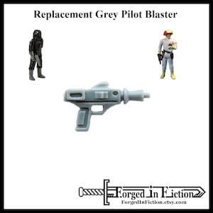 May include: A grey plastic blaster, a replacement part for a vintage action figure. The blaster has a handle, a barrel, and a rectangular sight.