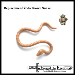 May include: A tan-colored, plastic snake toy, with a segmented body and a rounded head, is featured in this image. The text "Replacement Yoda Brown Snake" is at the top. A small Yoda figurine is in the upper right corner. The logo "Forged In Fiction" is at the bottom.