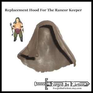 May include: A replacement hood for the Rancor Keeper action figure, in a muted brown color. The hood is made of a flexible material and is designed to fit the figure. The text "Replacement Hood For The Rancor Keeper" is at the top of the image.