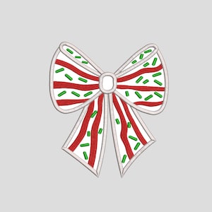 May include: A white bow with red and green stripes and green sprinkles. The bow is tied in a knot and has a white center.