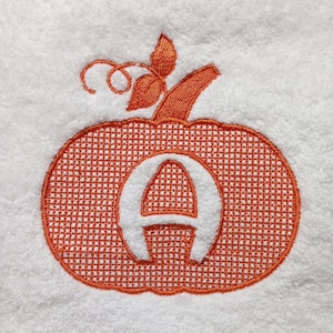 May include: Orange embroidered pumpkin with the letter A inside. The pumpkin has a stem and leaves.