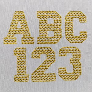 May include: Gold embroidered letters A, B, C, 1, 2, and 3 on a white fabric background.