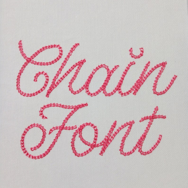 K&ouml;nnte beinhalten: Der Schriftzug "Chain Font" ist in rosa Garn auf einem wei&szlig;en Stoffgrund gestickt.
