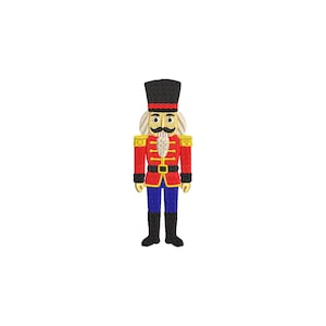 Puede incluir: Imagen bordada de un soldado cascanueces. El cascanueces viste una chaqueta roja con detalles dorados, pantalones azules y botas negras. Un sombrero negro con una banda roja corona la cabeza del cascanueces. El cascanueces tiene un bigote blanco y una expresión seria.