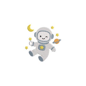 以下が含まれることがあります： 宇宙服を着て、星の杖を持った笑顔の宇宙飛行士の刺繍デザイン。黄色い星、三日月、輪のある惑星に囲まれています。デザインは白い背景にあります。