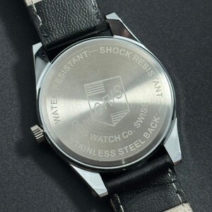 Puede incluir: Primer plano de la parte trasera de un reloj Oris plateado con una correa de cuero negro. La esfera del reloj indica "Water Resistant", "Shock Resistant" y "Stainless Steel Back". El logotipo de Oris es visible en el centro.