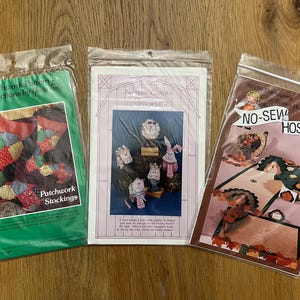 May include: Three craft patterns for making a patchwork stocking, a farmhouse themed door hanger, and a no-sew hostess rug. The patterns are printed on white paper with colorful illustrations.
