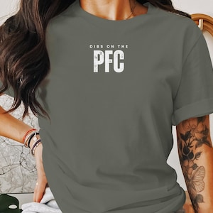 May include: A green t-shirt with the text "DIBS ON THE PFC" in white.