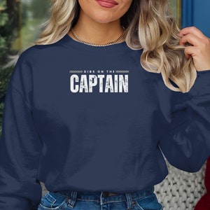 May include: A navy blue sweatshirt with the text "DIBS ON THE CAPTAIN" in white lettering.