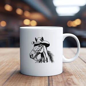 May include: White ceramic mug with a black and white illustration of a horse wearing a cowboy hat. The horse is looking to the left.