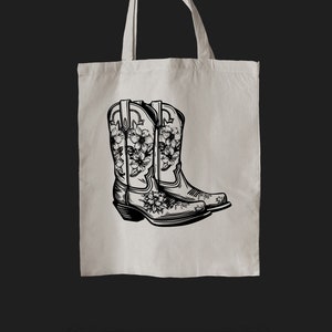 May include: A tote bag with a black and white illustration of two cowboy boots with floral designs.