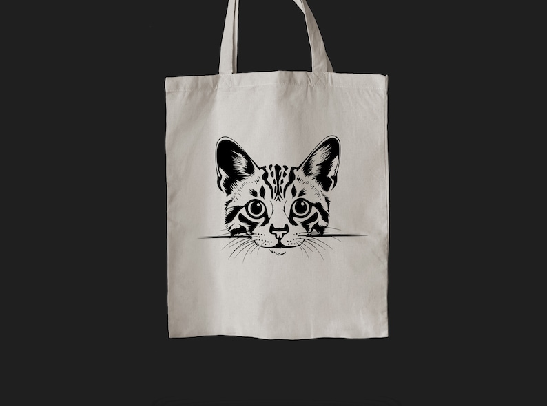 Pu&ograve; includere: Una borsa tote bianca con un'illustrazione in bianco e nero di un viso di gatto che sporge dalla parte superiore.