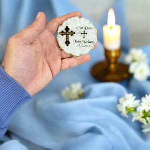 May include: A white seashell with a gold trim and a cross charm. The seashell has the text "God Bless Jean Luciano 10.10.2024" and "Jean's Baptism 2024.10.10" printed on it.