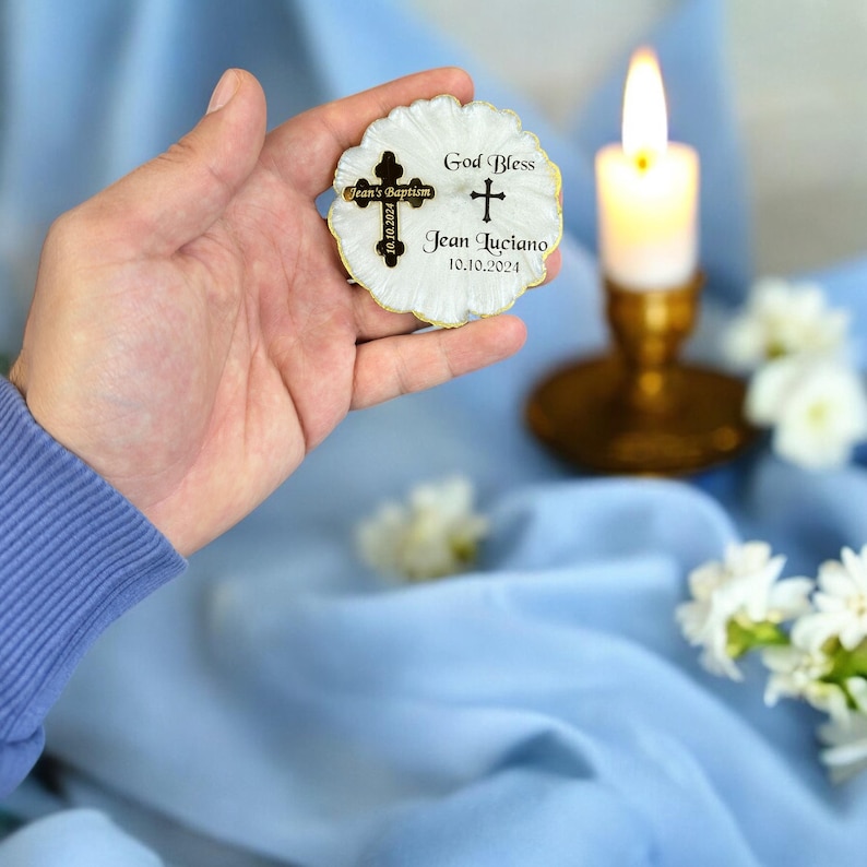 May include: A white seashell with a gold trim and a cross charm. The seashell has the text "God Bless Jean Luciano 10.10.2024" and "Jean's Baptism 2024.10.10" printed on it.