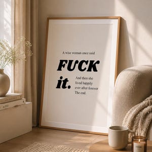 Könnte beinhalten: Gerahmter Kunstdruck mit dem Text "FUCK it." in fetten schwarzen Buchstaben. Das vollständige Zitat lautet: "Eine weise Frau sagte, Und dann lebte sie glücklich und zufrieden für immer. Ende." Der Druck befindet sich in einem Raum mit neutralen Tönen.