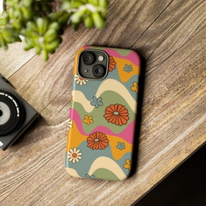 Pode incluir: Capa de telefone colorida com um design floral retrô. A capa apresenta um padrão ondulado em tons de laranja, rosa, verde e azul, com várias ilustrações de flores. Projetada para um smartphone, possui um recorte para a câmera.