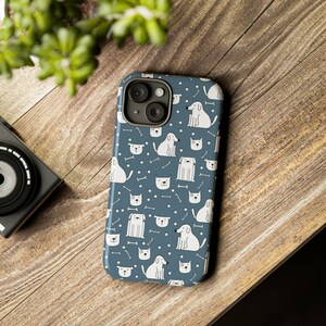 May include: A blue phone case with a white pattern of dogs and bones. The case has a camera lens cutout.