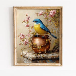 May include: A framed painting of a blue and yellow bird perched on a copper pot. Pink flowers and green vines surround the pot, set against a soft, neutral background. The artwork is in a gold-colored frame.