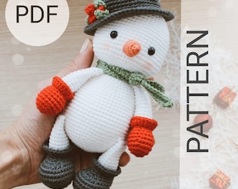 May include: Crochet pattern PDF for a snowman amigurumi toy. The snowman is wearing a grey hat, green scarf, and red mittens. The pattern is available for download.