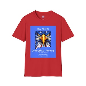 May include: A red t-shirt featuring a graphic of an eagle's face with blue, white, and red details. The graphic is set against a blue background and includes the text "NEW MEXICO" and "CELEBRATING AMERICA".