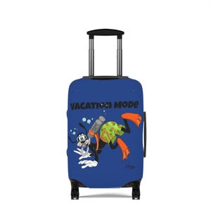 Peut inclure: Une valise à roulettes bleue avec un dessin animé de chien faisant de la plongée sous-marine, équipé d'un masque, d'un tuba et de palmes orange. Le chien porte un short vert à motifs ananas. Le texte VACATION MODE est inscrit en noir.