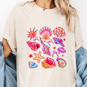 Camiseta colorida con estampado de conchas marinas, camiseta estética para un viaje de verano a la playa, camiseta con vibras oceánicas tropicales, camiseta cómoda con colores pastel y coquetos estampados de conchas marinas