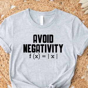 May include: A gray t-shirt with the text "AVOID NEGATIVITY f(x) = |x|" printed in black.