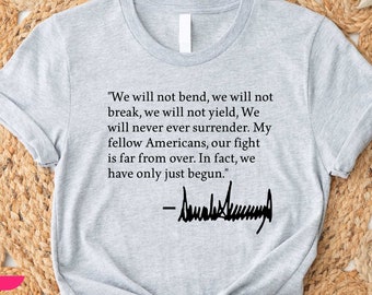 May include: A light gray t-shirt with a quote in black text: "We will not bend...our fight is far from over. In fact, we have only just begun." The quote is followed by a signature. The shirt is knotted at the bottom.