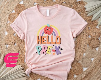 May include: Pink t-shirt with a rainbow and a smiling apple graphic. The text "Hello Pre-K" is printed on the shirt.
