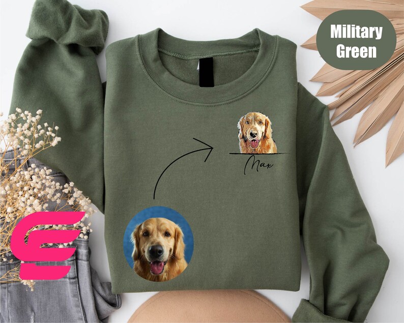 K&ouml;nnte beinhalten: Ein olivgr&uuml;nes Sweatshirt mit einem wei&szlig;en Pfeil, der auf ein Foto eines Golden Retriever-Hundes mit dem Namen "Max" darunter zeigt. Das Sweatshirt zeigt auch ein kleineres Foto des Hundes in der linken unteren Ecke.