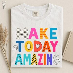 A white t-shirt with the text "MAKE TODAY AMAZING" printed on it in a colorful, playful font.